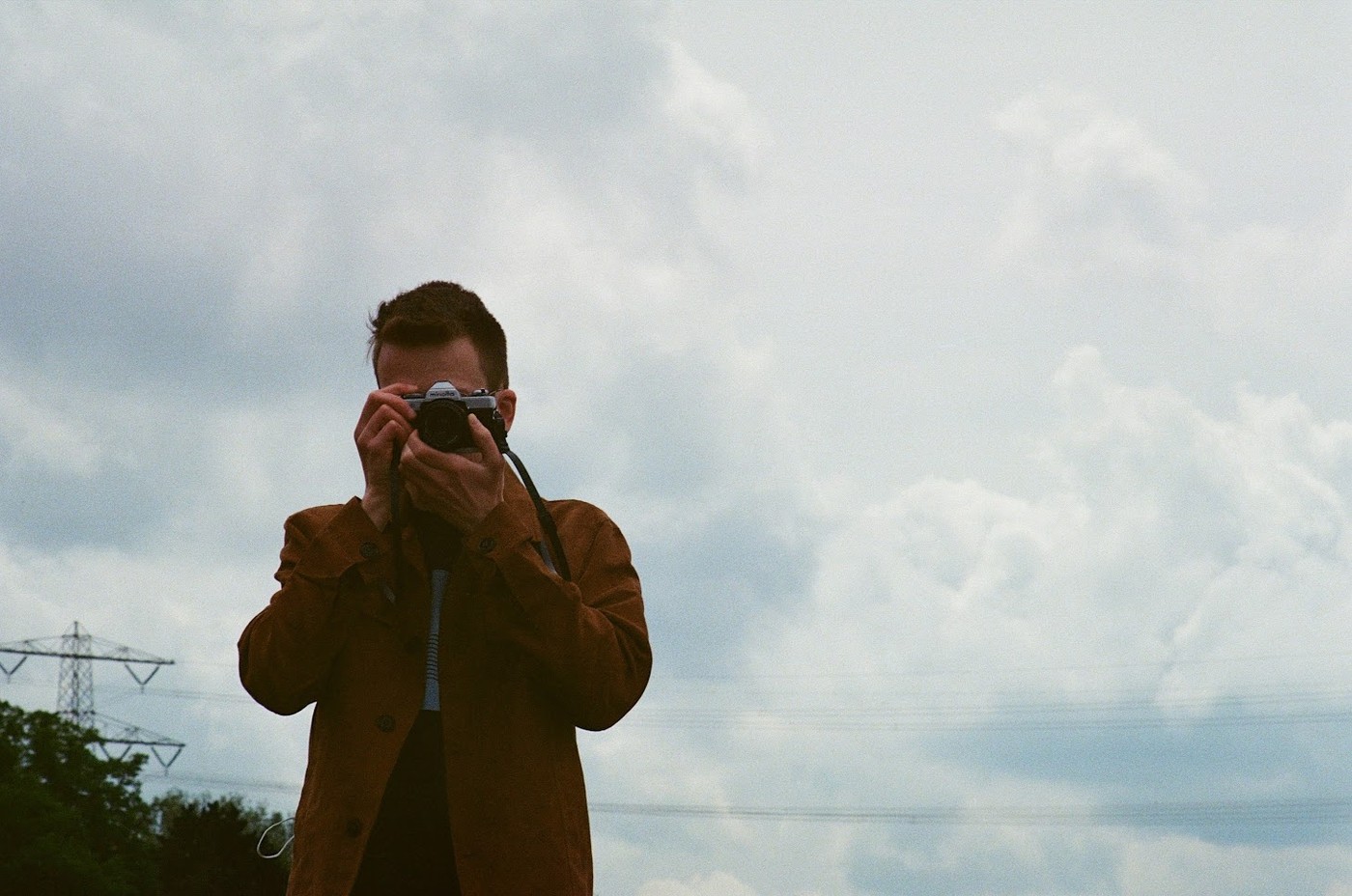 Arne Reijntjes kijkt met een analoge fotocamera recht naar de kijker